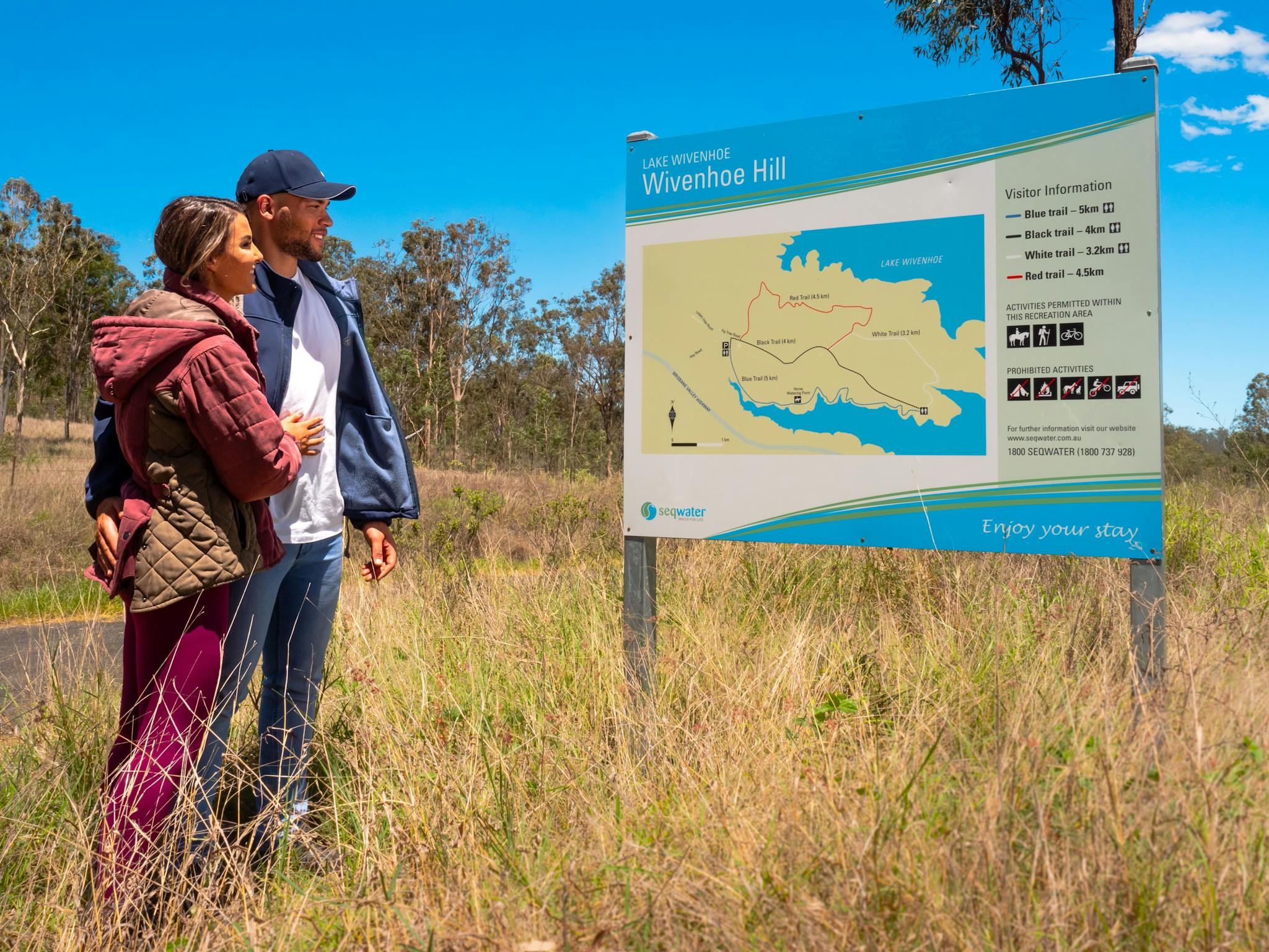 Couple looking at the Wivenhoe Hill Trails walking sign in Somerset Couple looking at the Wivenhoe Hill Trails walking sign in Somerset