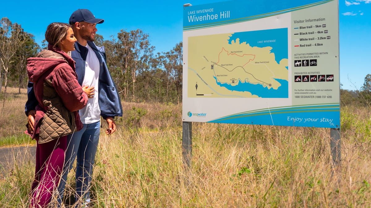Couple looking at the Wivenhoe Hill Trails walking sign in Somerset
