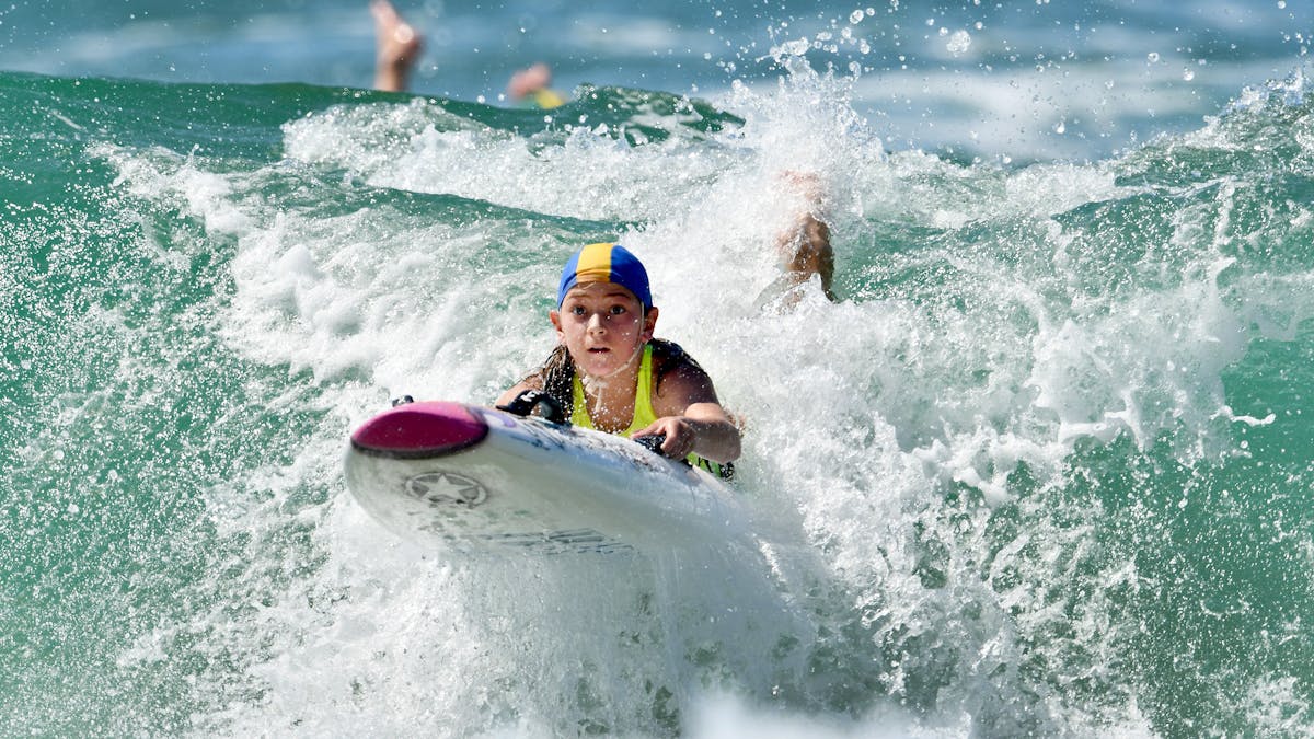 A 2024 Coolangatta Gold Youth Challenge competitor catches a wave