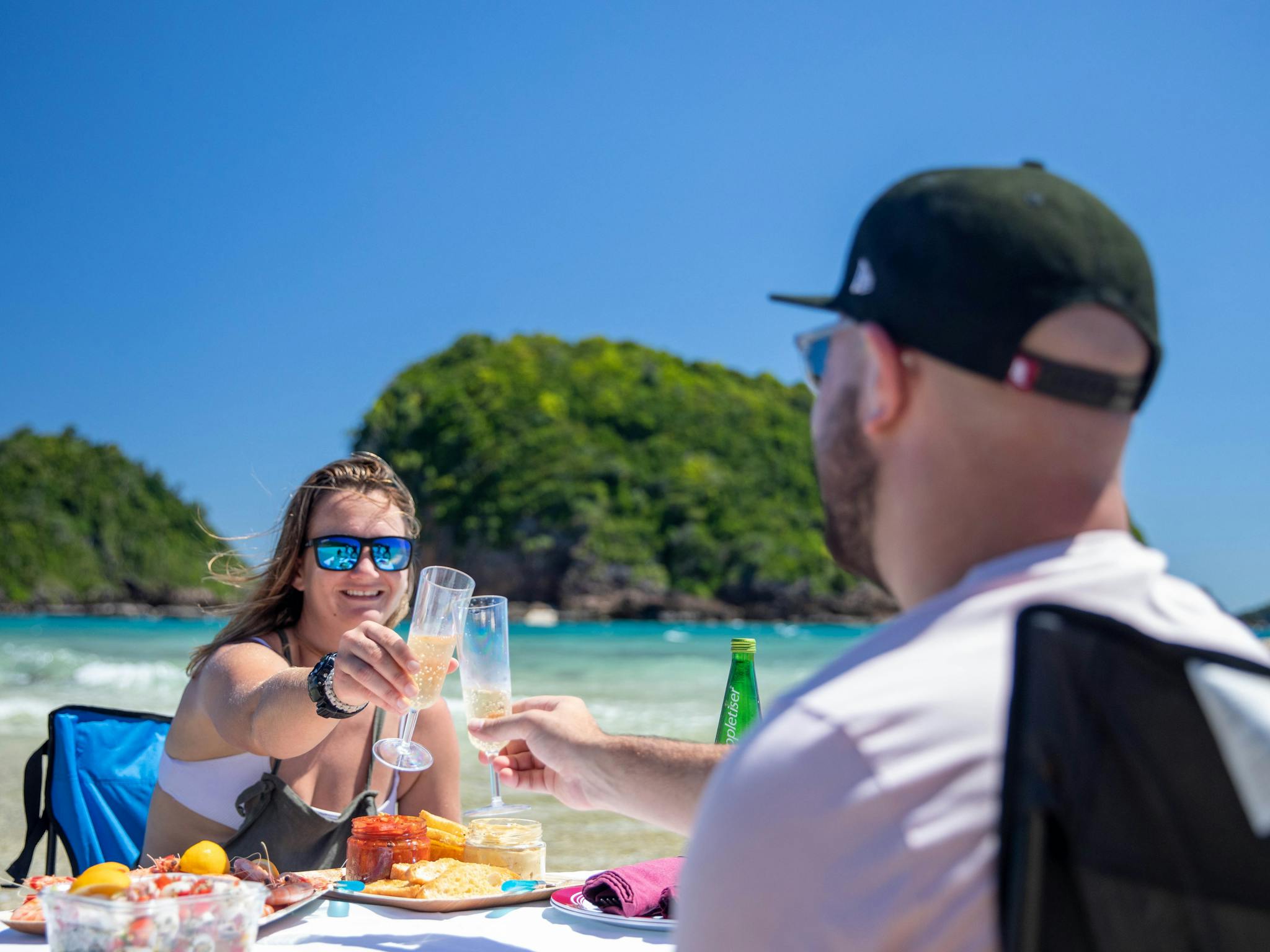 A caucasian couple toasts each other over a seafood lunch on a tropical island A caucasian couple toasts each other over a seafood lunch on a tropical island
