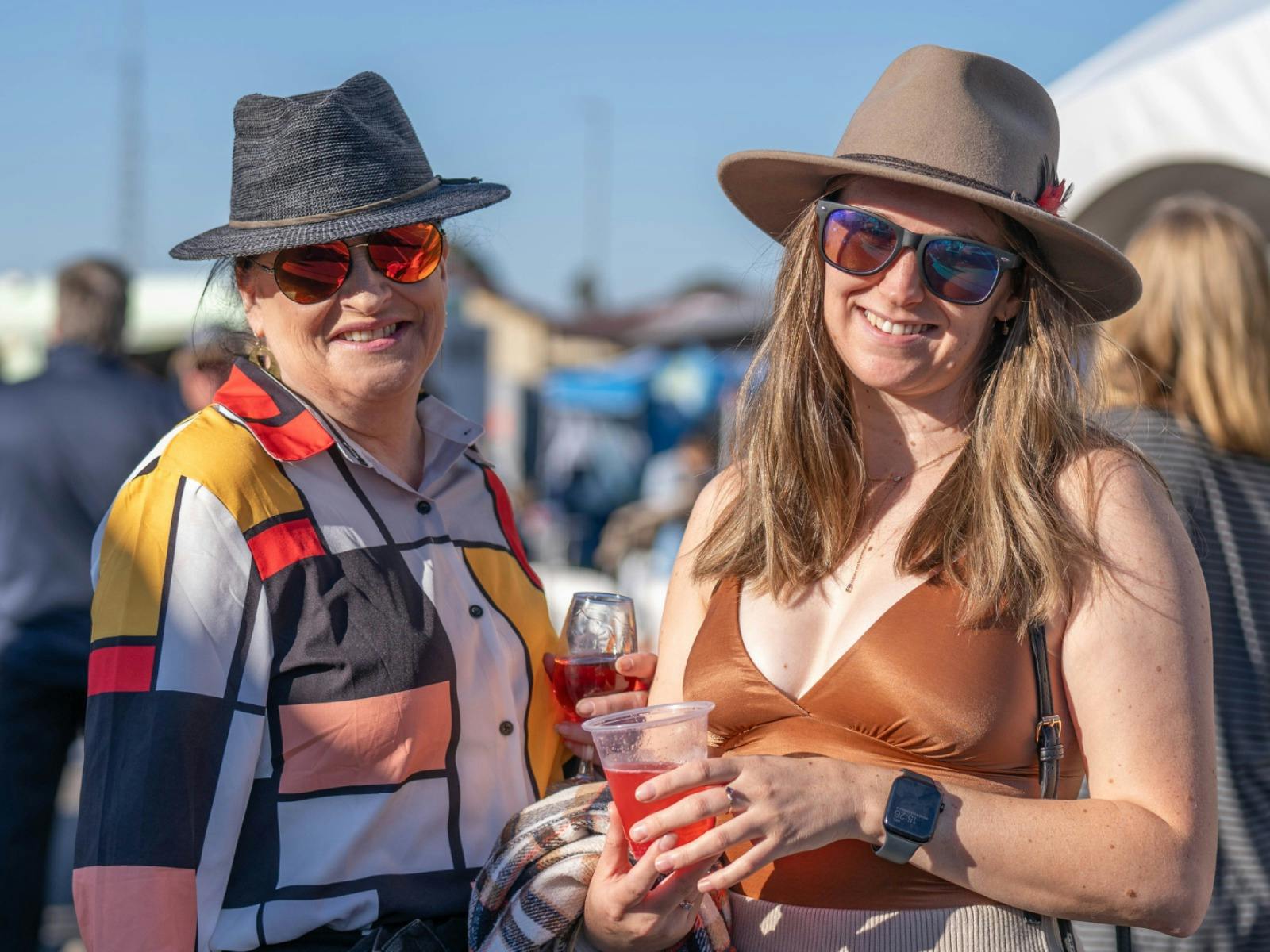 two people smiling in the sun enjoying wine