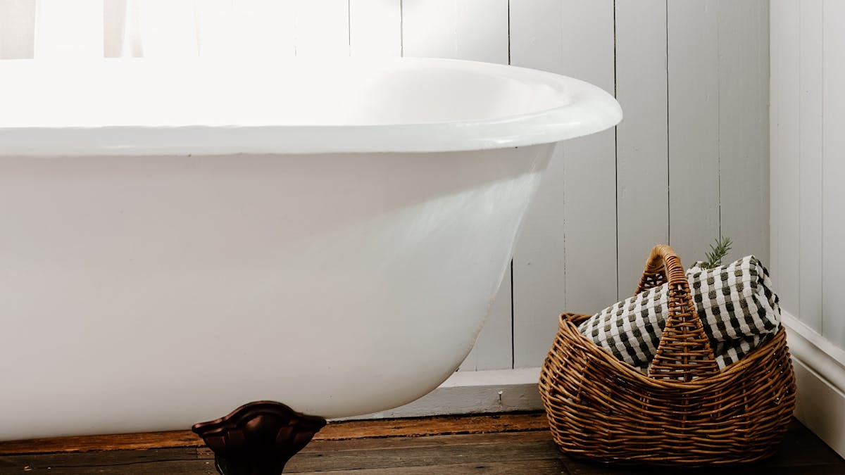 Styled photo of a traditional clawfoot bath, with gorgeous curtain and beautiful lighting