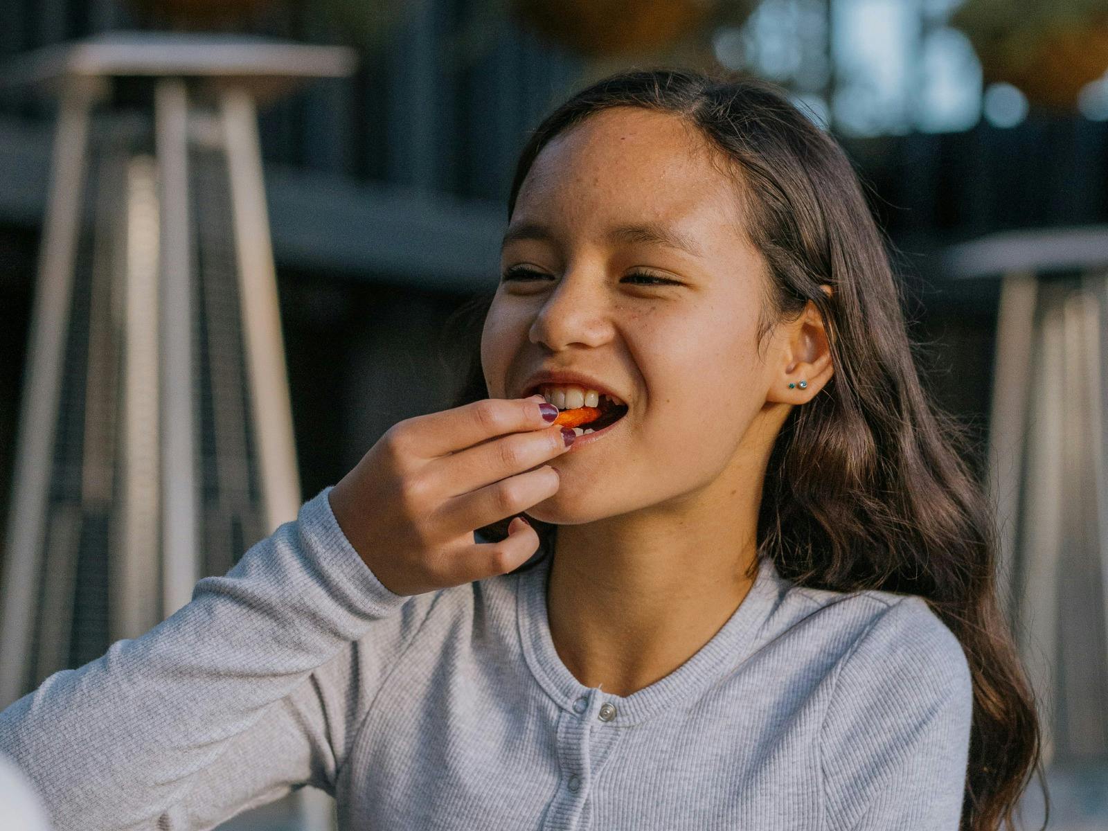Smiling girl eating a chip outdoors at Easy Tiger in St Helens.