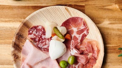 Antipasto platter on wooden table with bottle of wine