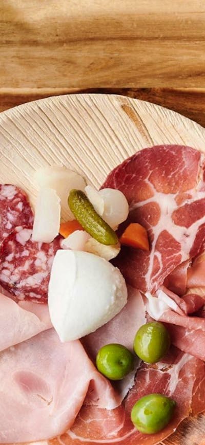 Antipasto platter on wooden table with bottle of wine