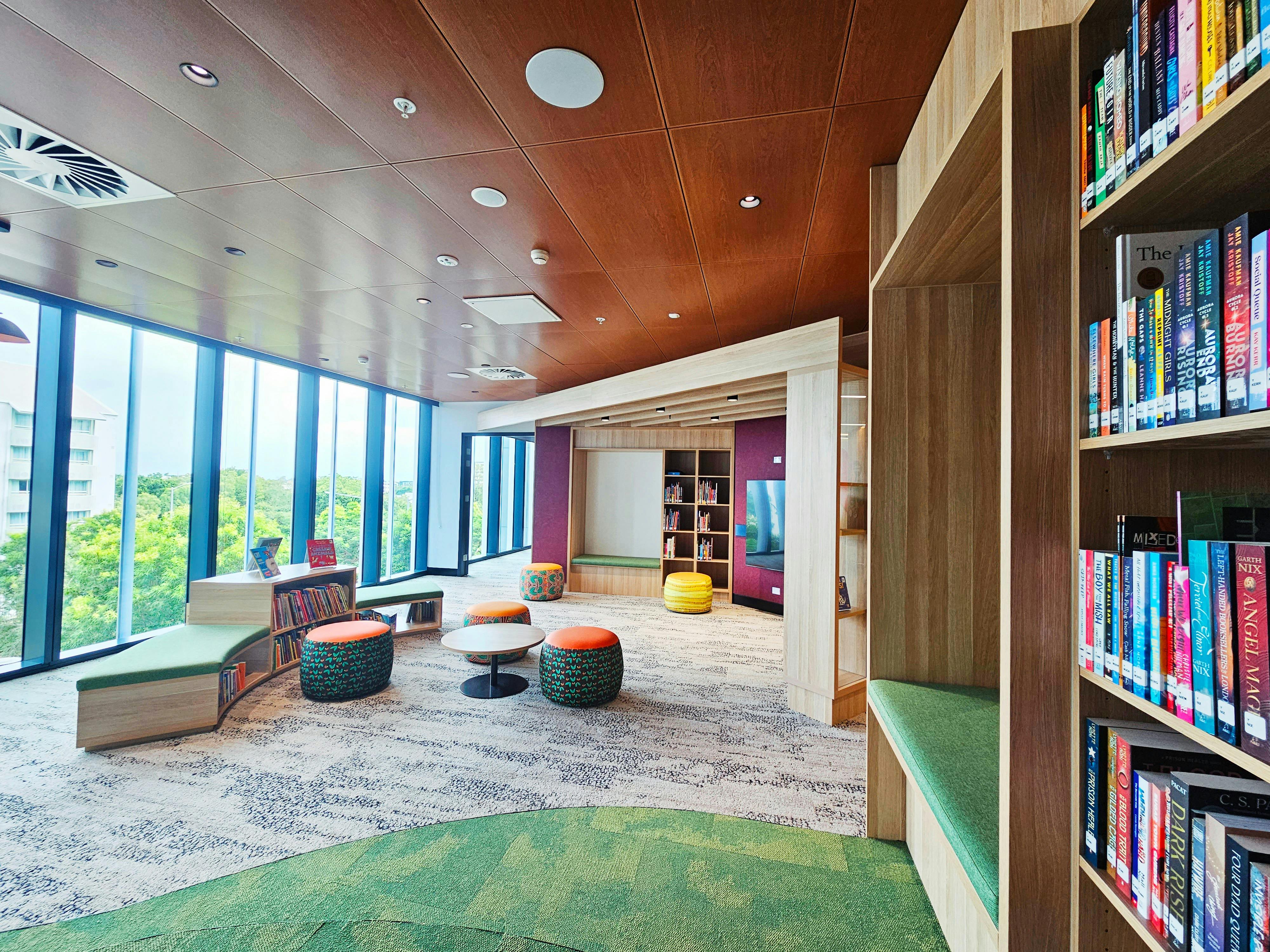 Bookshelves in a brightly lit room with a wall of windowds