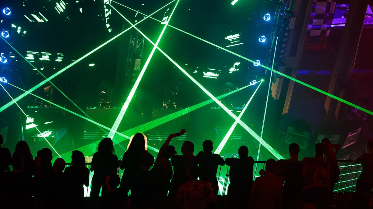 Image depicts a rave with shadows and green lights