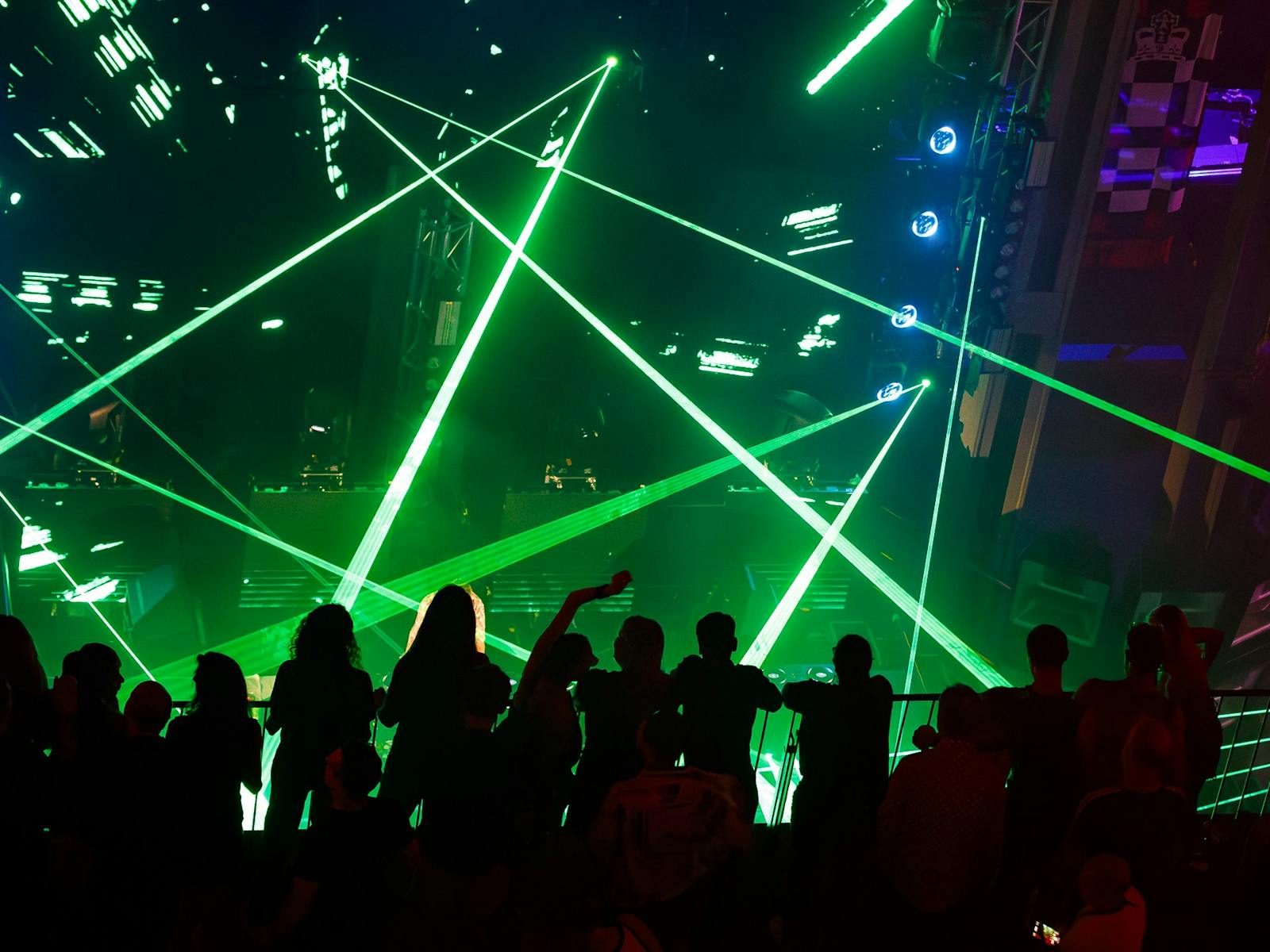 Image depicts a rave with shadows and green lights Image depicts a rave with shadows and green lights