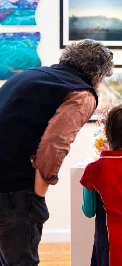 A man and a boy looking at sculptures on a plinth
