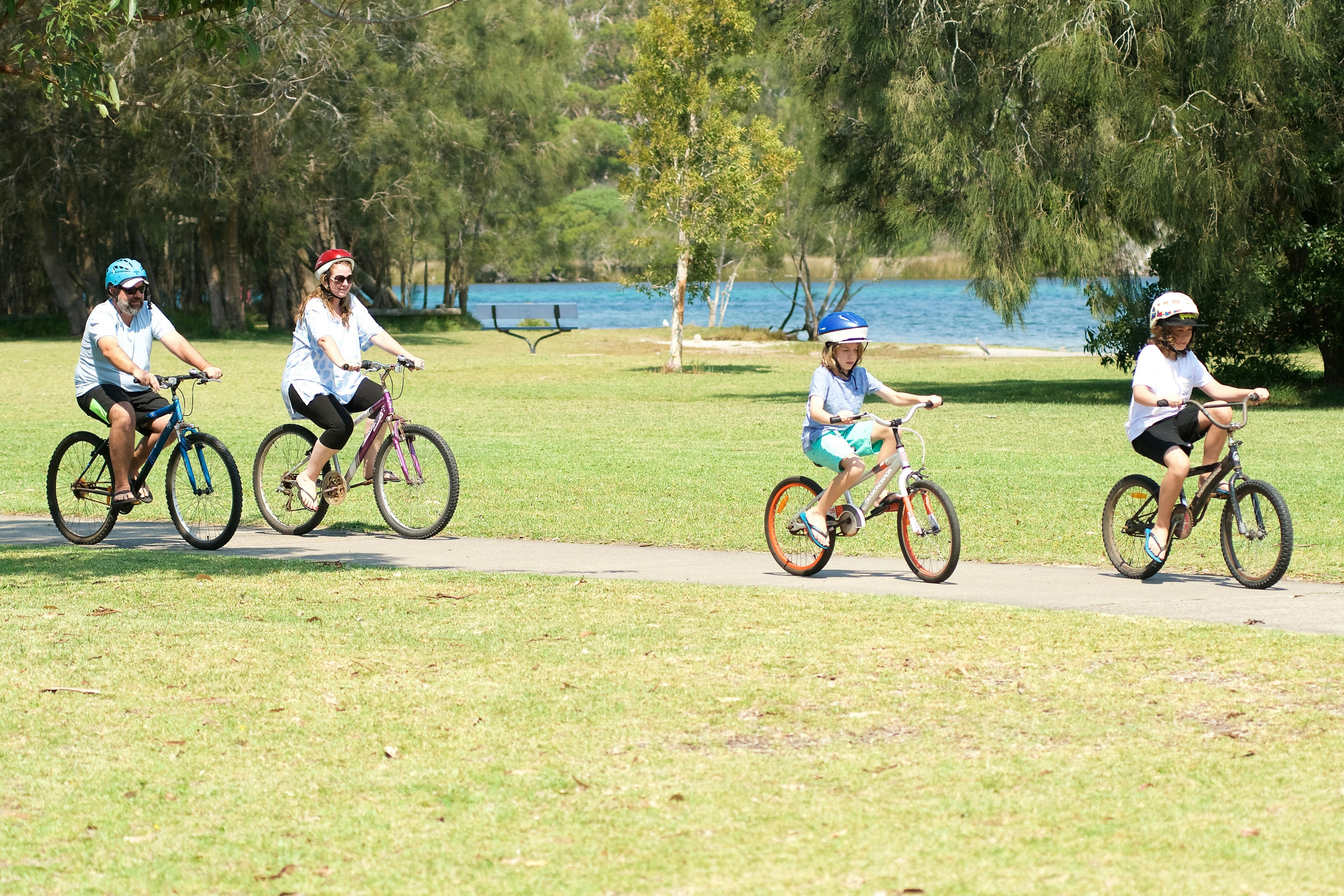 Guests bike riding on path along water