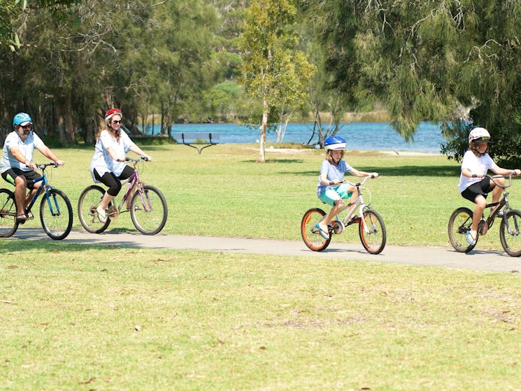 Guests bike riding on path along water