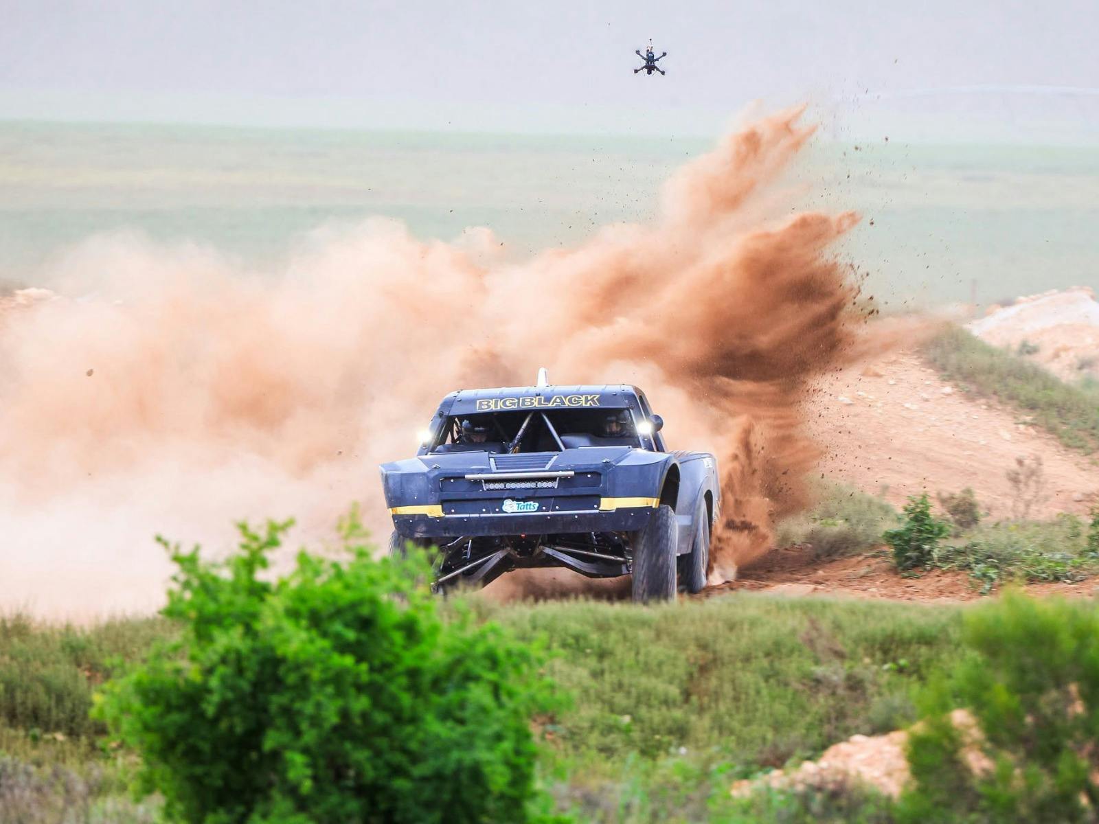 Trophy truck throwing dirt behind.