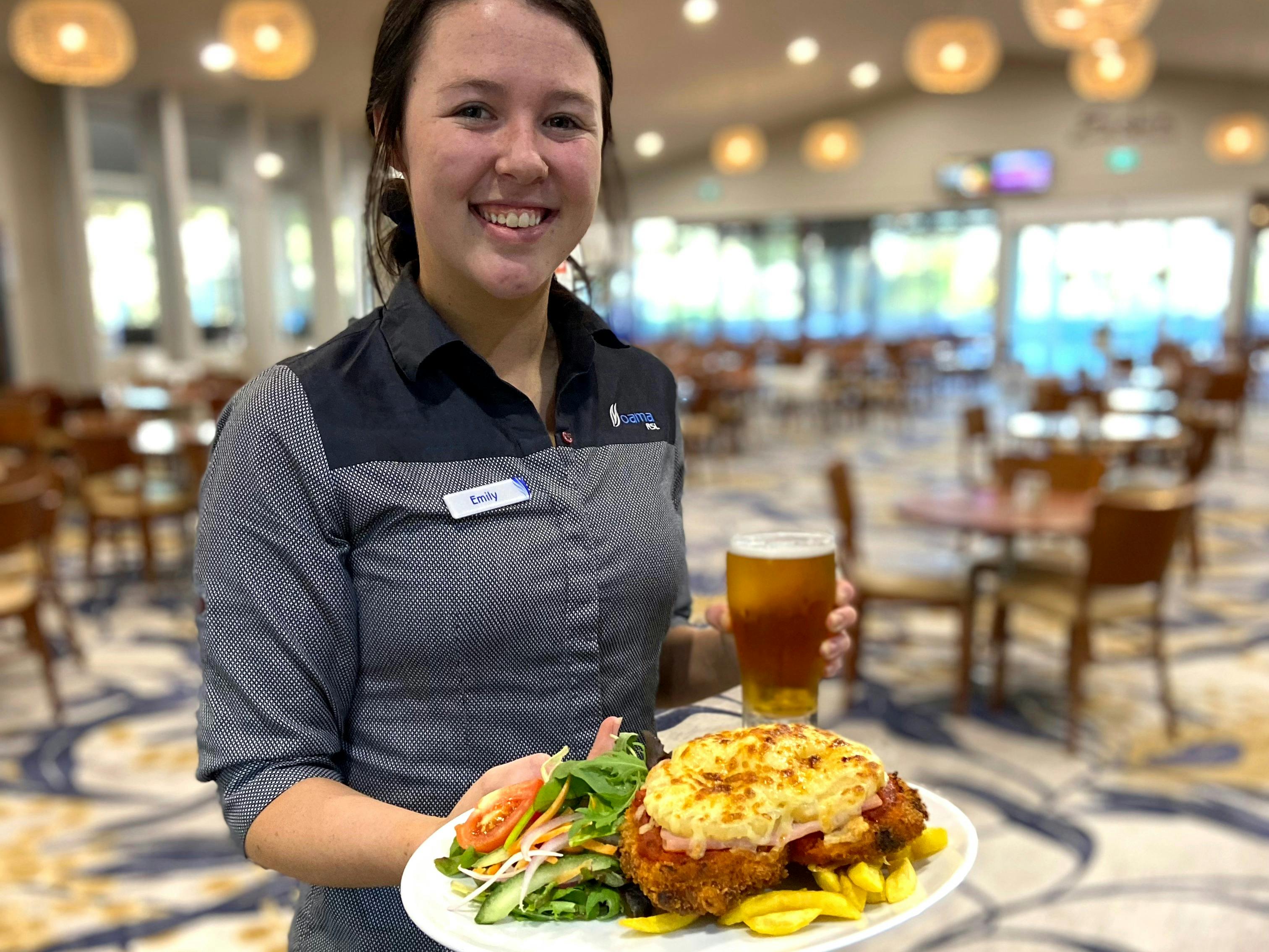 Female staff member holding a pot of beer and a chicken parmigiana