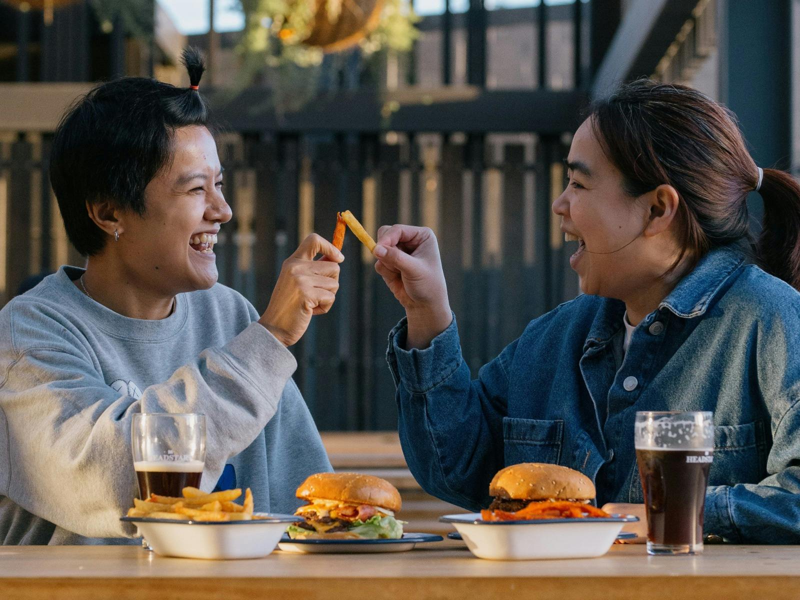 Two women sharing fries with burgers at Easy Tiger in St Helens.