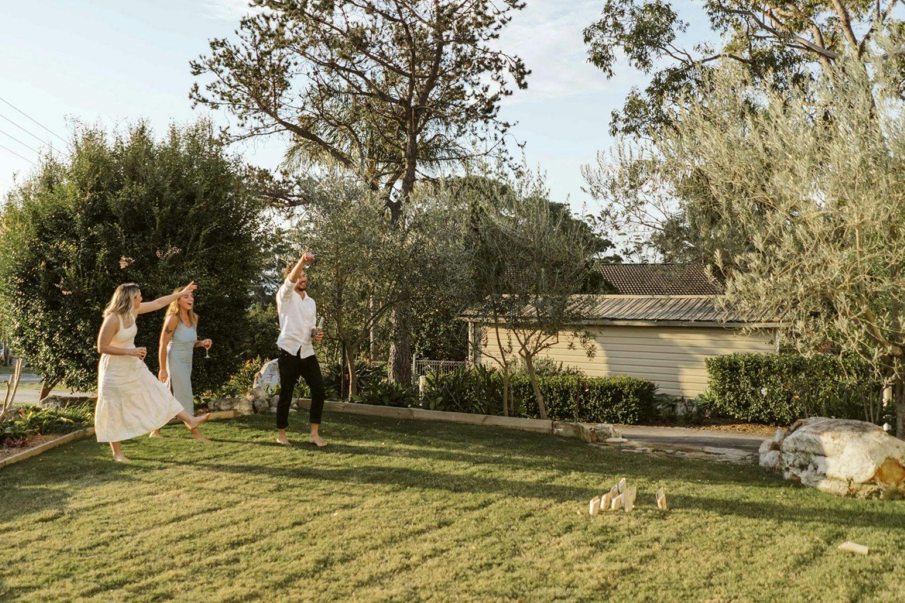Image of three people enjoying a game. Guests are barefoot on the grassed front outdoor yard.