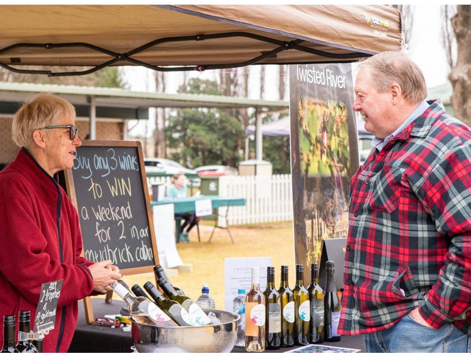 市場の屋台で男性にワインを売る女性