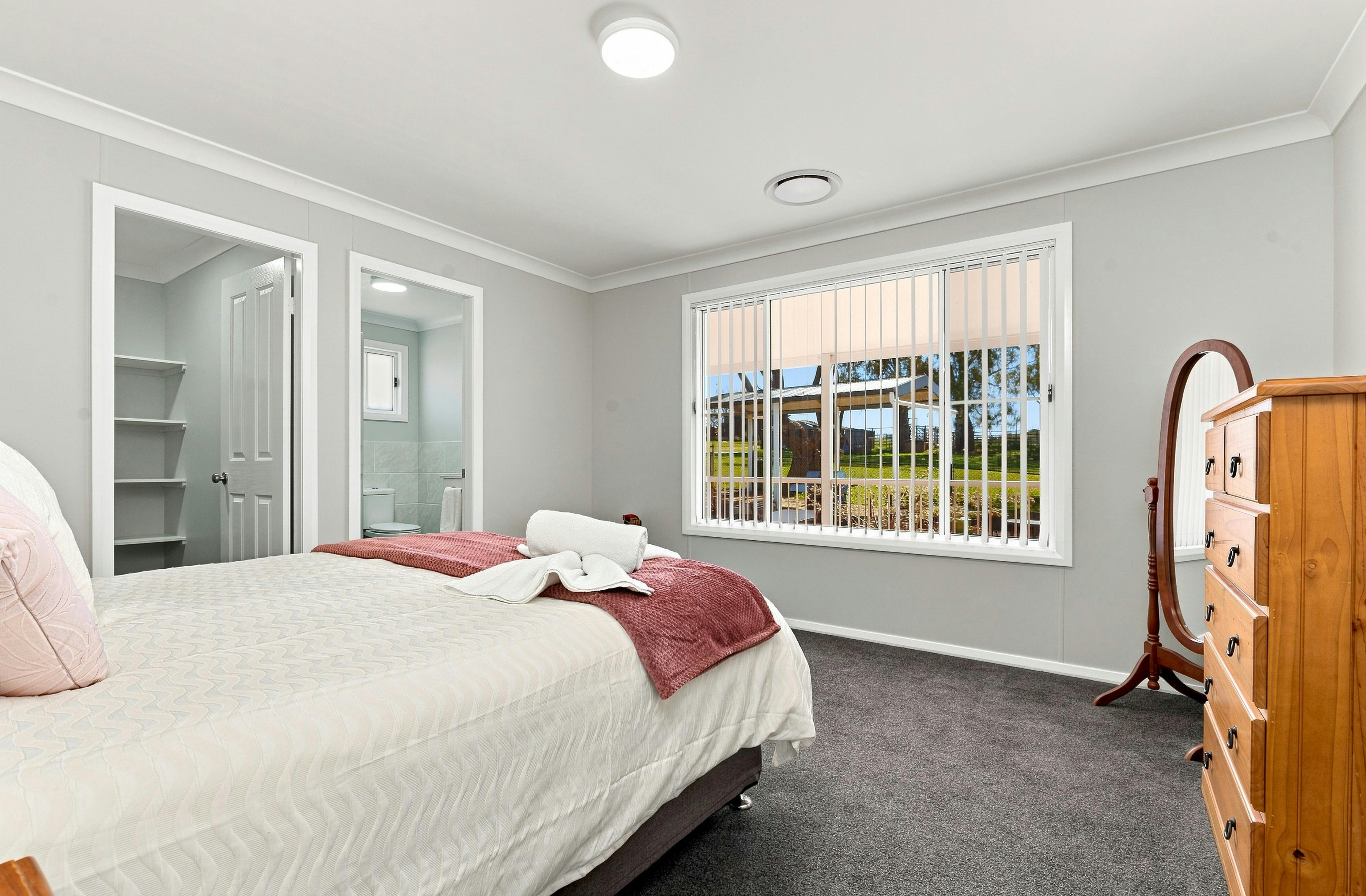 King bed, ensuite and walk in robe. Grey carpet, stand alone mirrow and large window