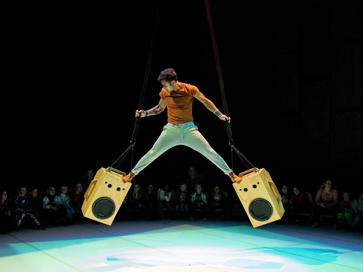 A man standing on two speakers.