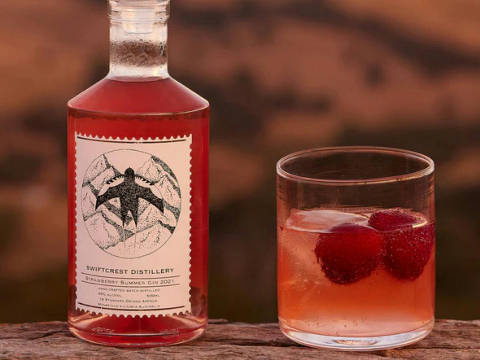 Gin bottle with pink gin plus glass with strawberry in it