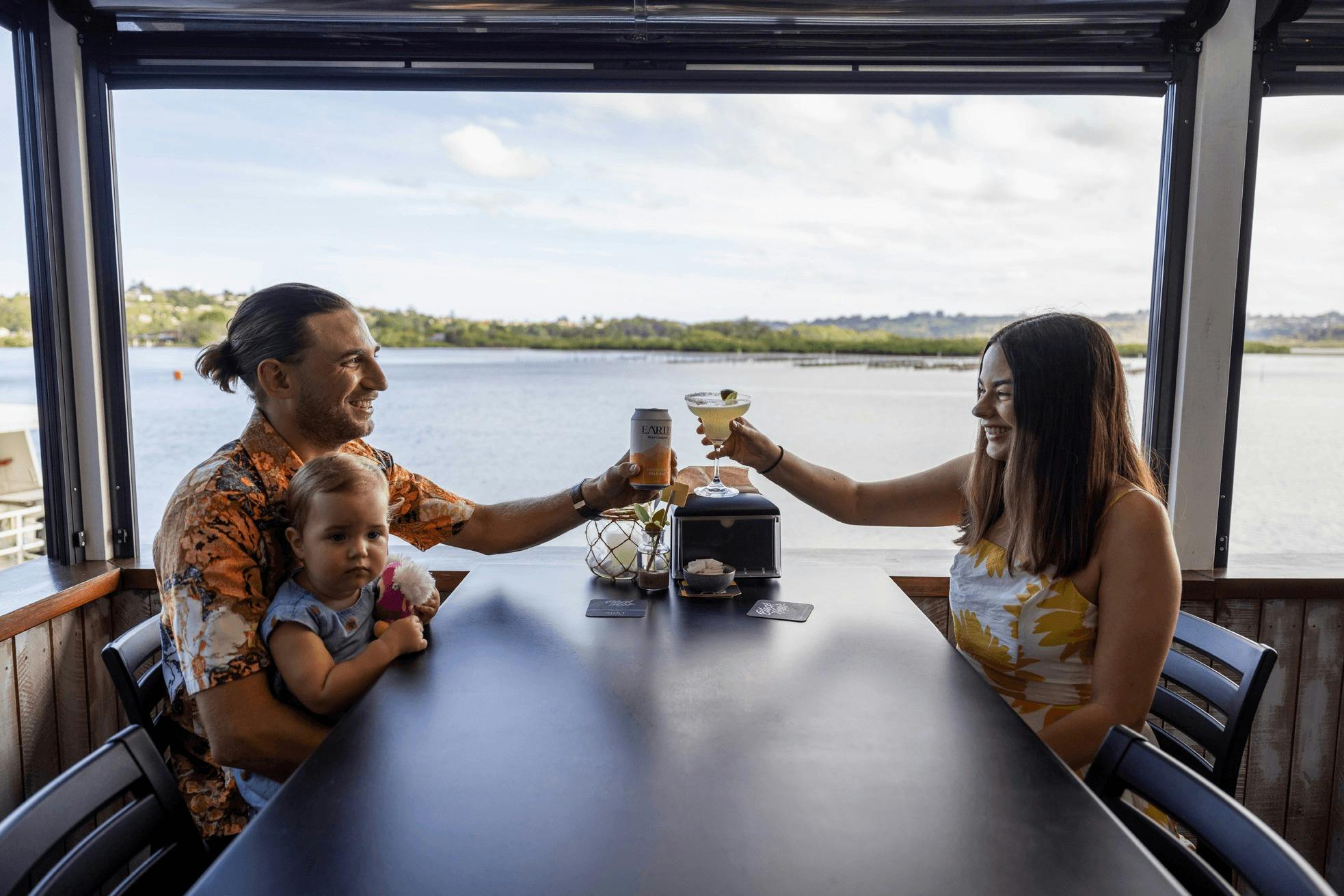 Young couple with baby enjoy a family meal at The Oyster Shed, Tweed River, NSw