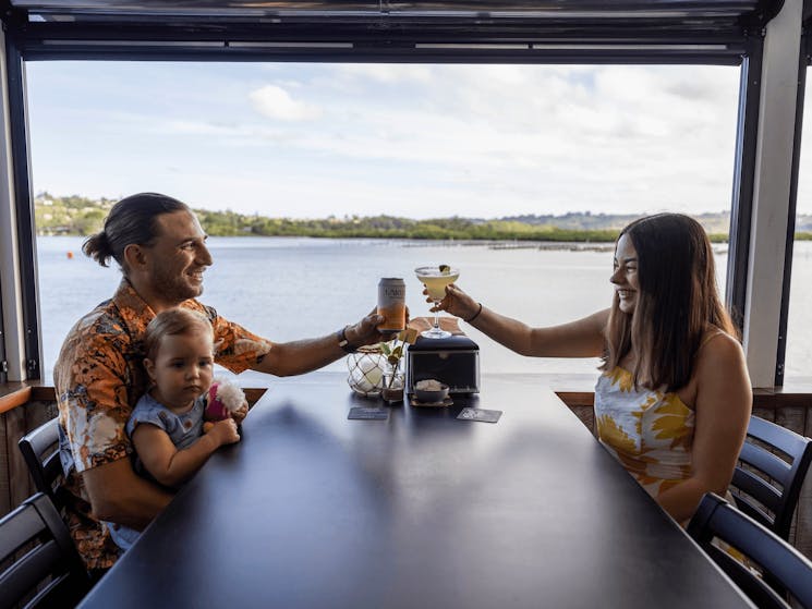 Young couple with baby enjoy a family meal at The Oyster Shed, Tweed River, NSw