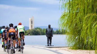 Group of cyclists going past the R G Menzies statue on the Lake Burley Griffin foreshore