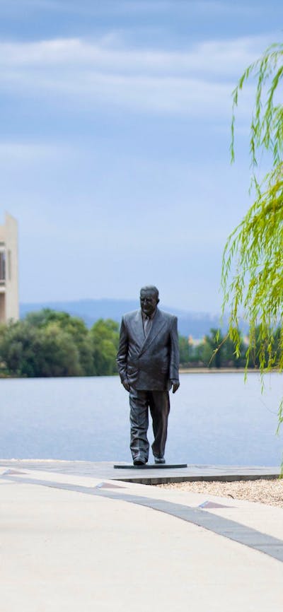 Group of cyclists going past the R G Menzies statue on the Lake Burley Griffin foreshore