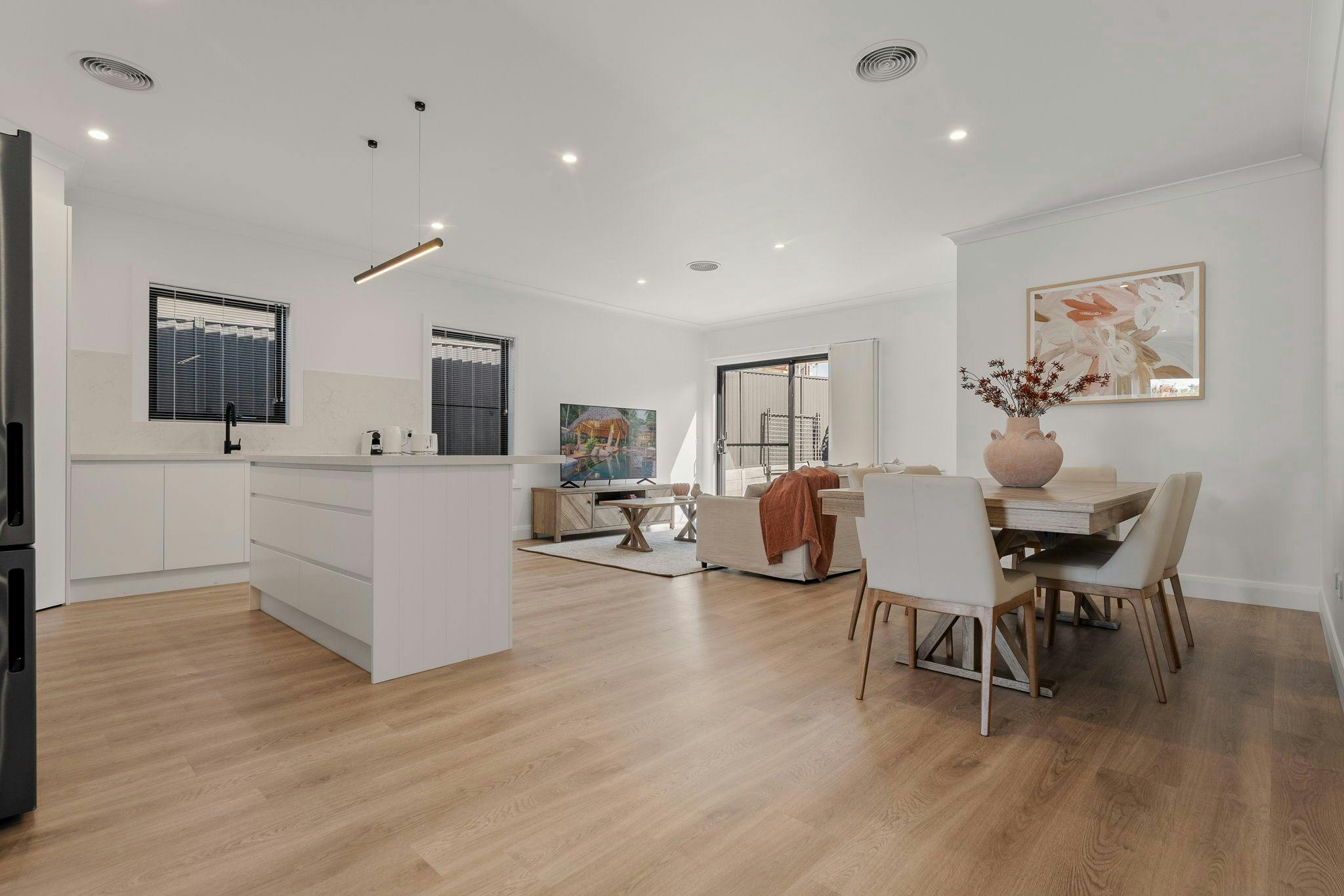 Large living area, dining table and kitchen with timber flooring.