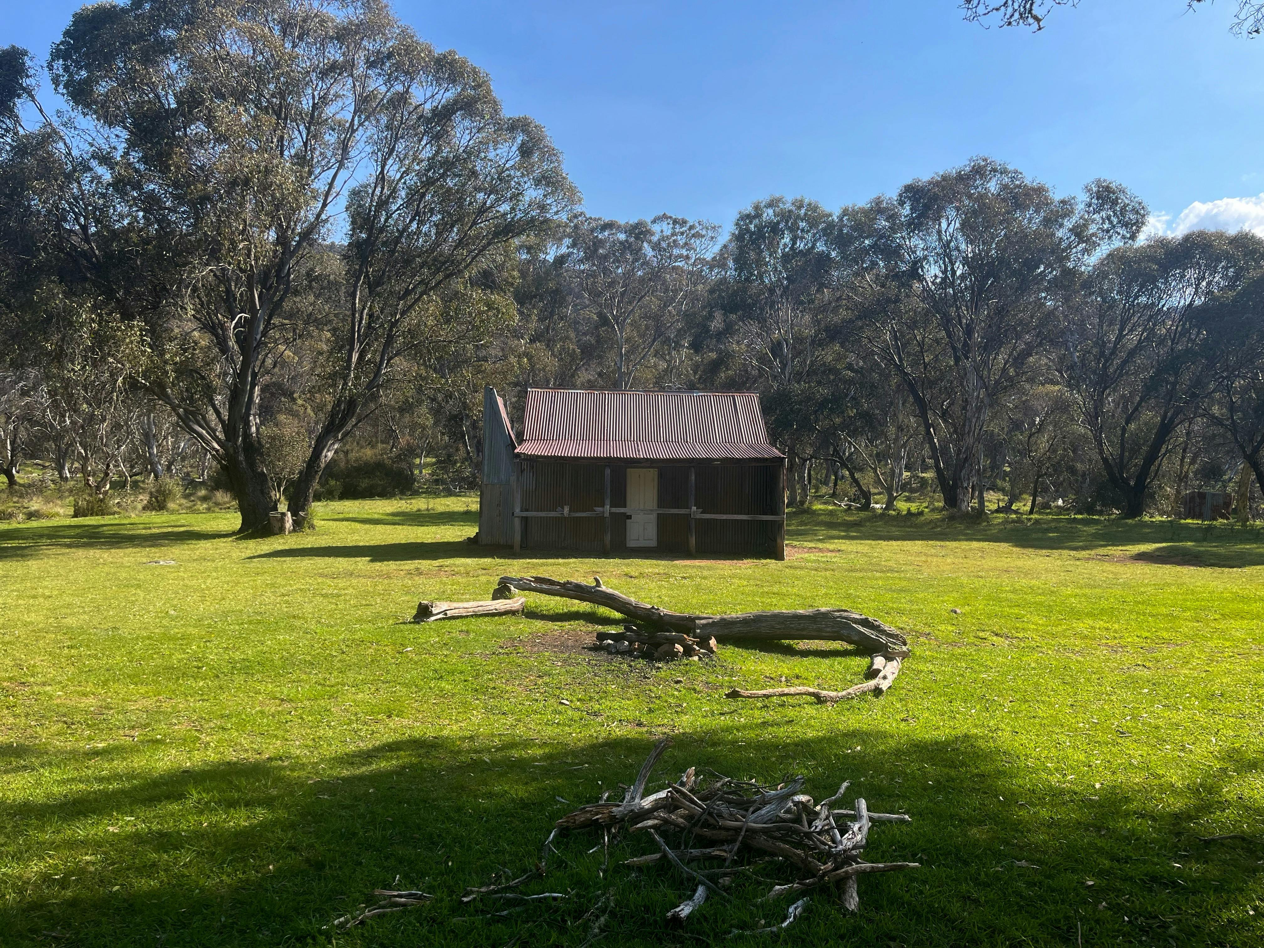 A hut in the middle of an open field with some trees in the background.