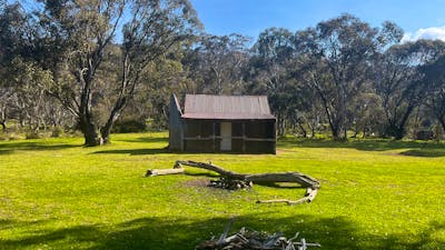 A hut in the middle of an open field with some trees in the background.