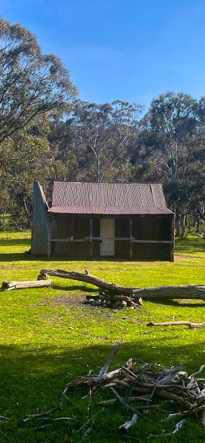 A hut in the middle of an open field with some trees in the background.