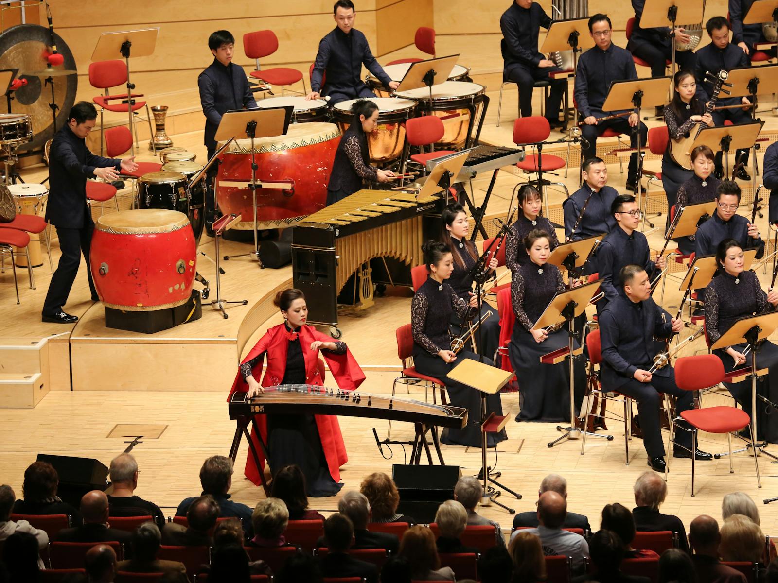 Shanghai Chinese Orchestra live performance featuring a guzheng soloist in red with full ensemble.