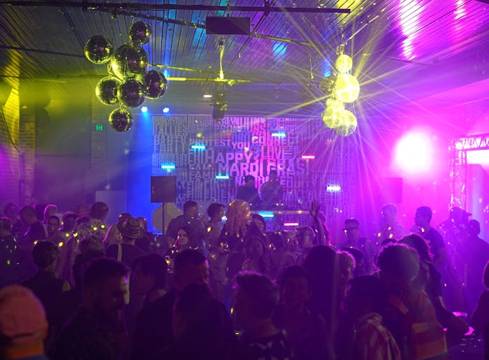Two DJs performing for a large group at a late-night venue