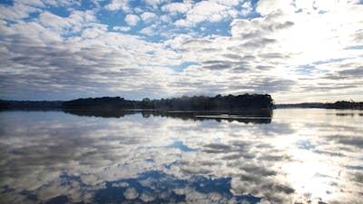Lake Ginninderra on a sunlit day with clusters of clouds.