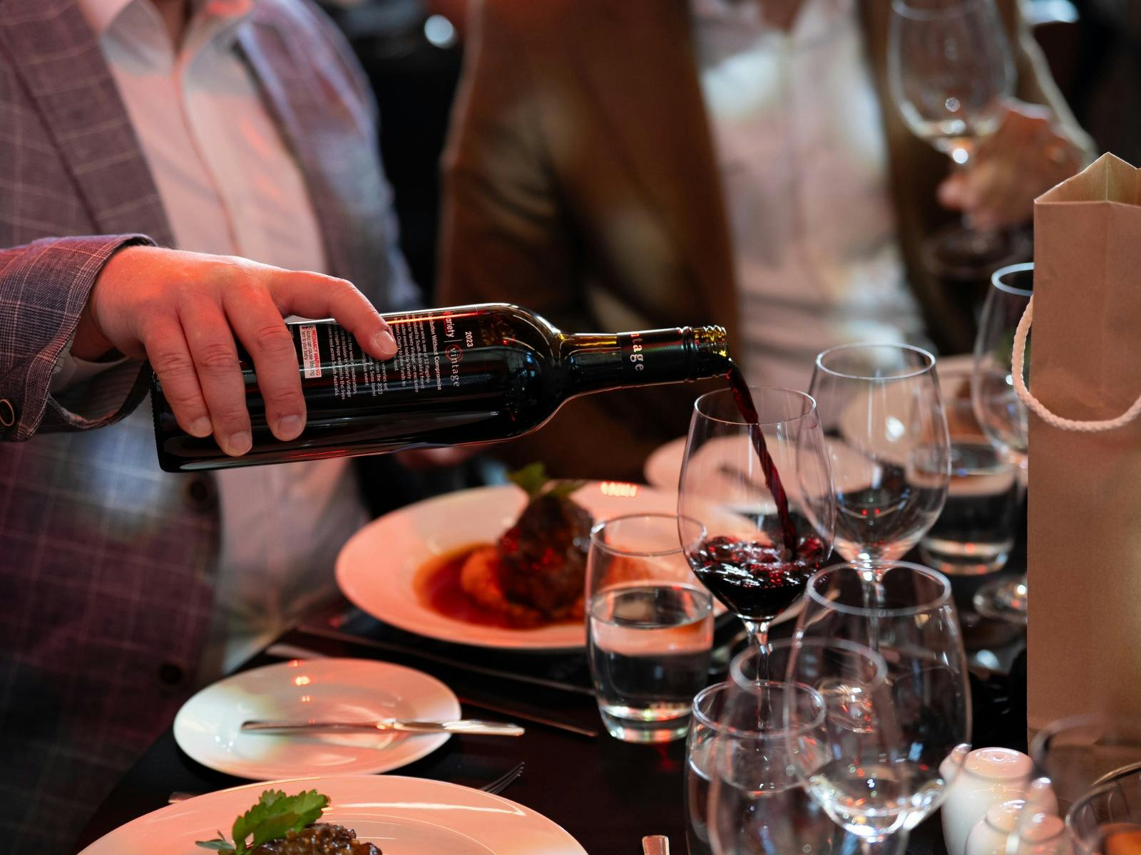 Man pouring red wine with lunch