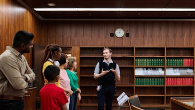 A MoAD Museum Experience Officer speaks to a group of people gathered in the Prime Minister's office