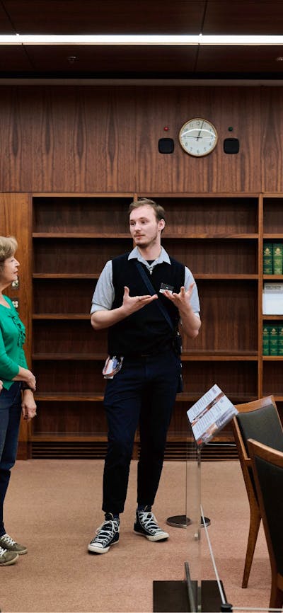 A MoAD Museum Experience Officer speaks to a group of people gathered in the Prime Minister's office