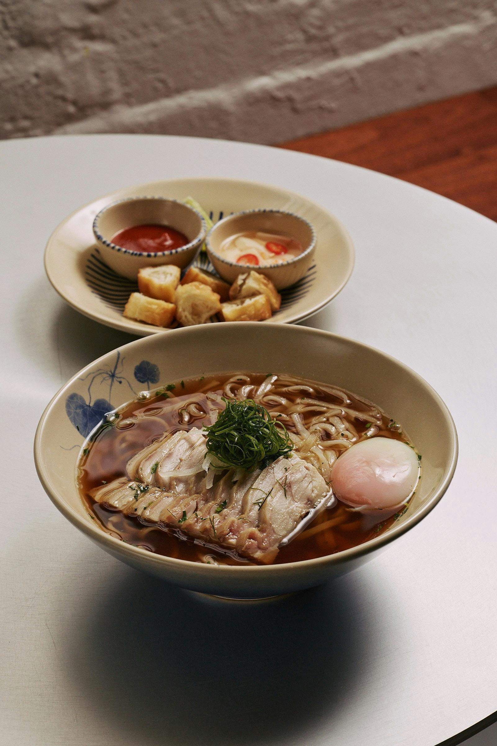 Free-range chicken thigh cooked in masterstock with 12-hour broth, 63°C egg, herbs and Chinese donut