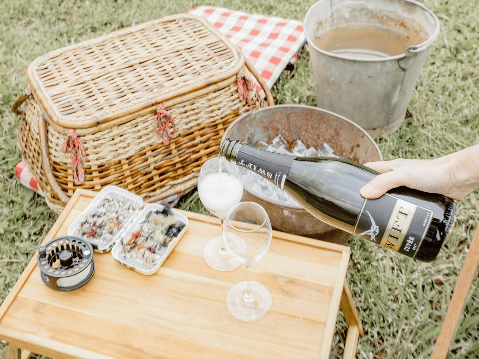 Glass of sparkling on table near water. Fly Fishing Experience