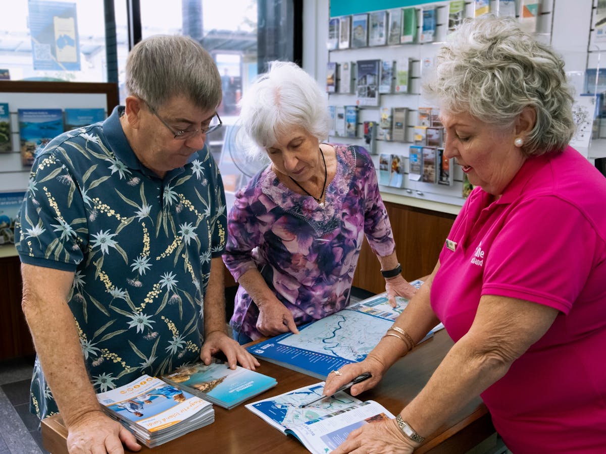 Female volunteer in Pink shirt assisting two visitors