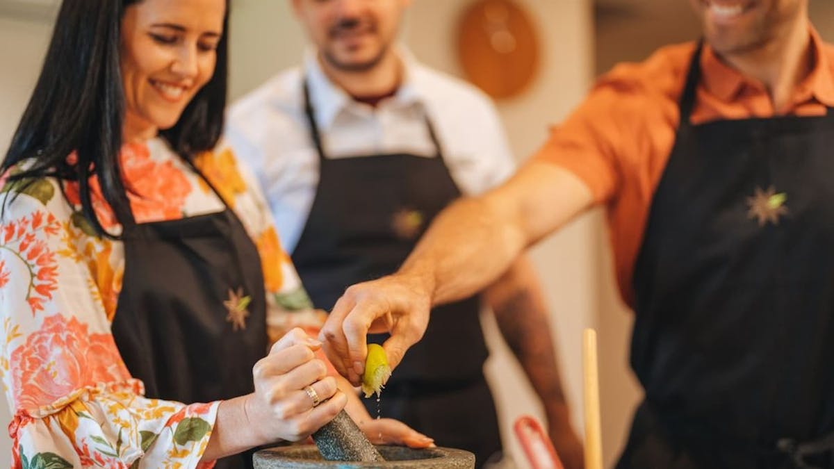 Three people in a cooking class wearing aprons