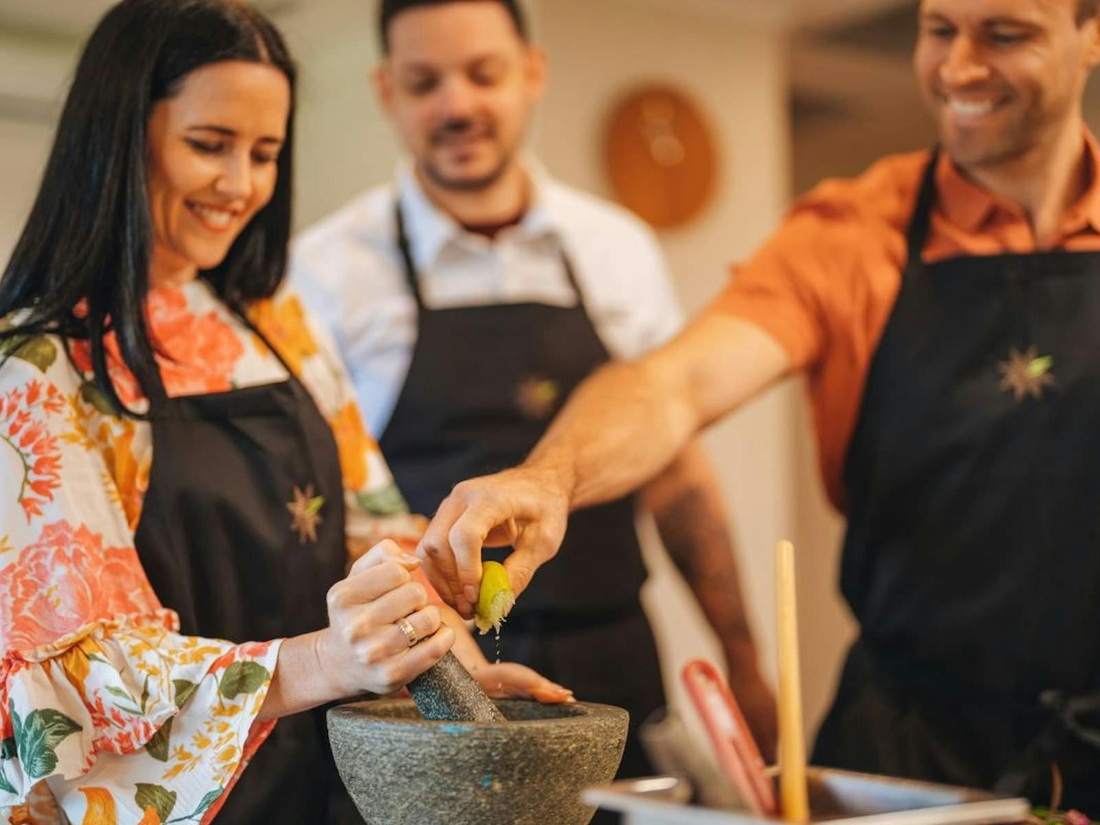 Three people in a cooking class wearing aprons Three people in a cooking class wearing aprons