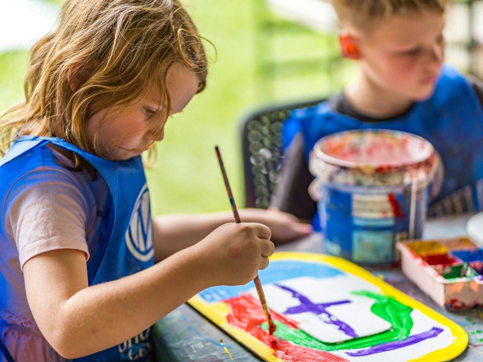 A girl paints a shield in bright colours.