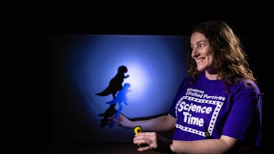 A woman making a dinosaur shadow in Science Time