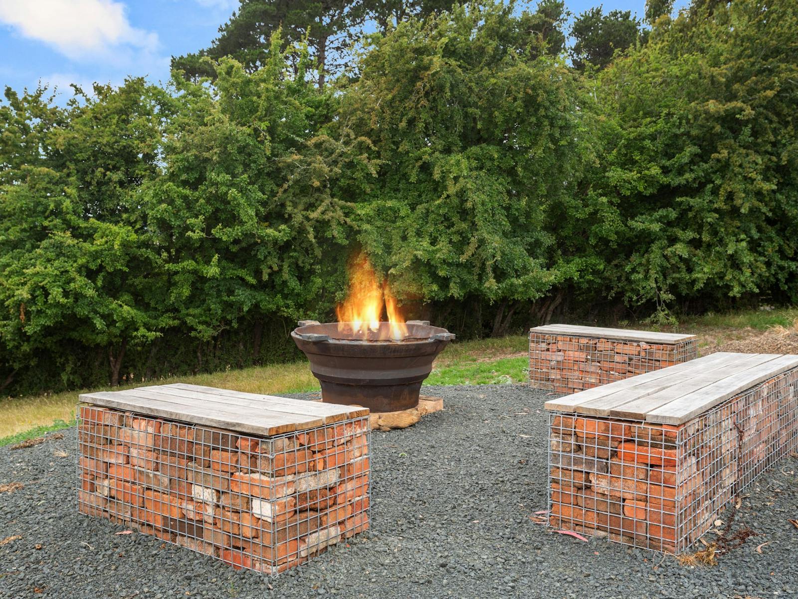Fire coming out of rustic iron firpit with stone brick seating around it