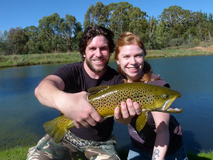 Young couple holding big brown trout