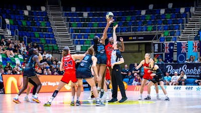 Basketball players mid-jump while competing for the tip-off.
