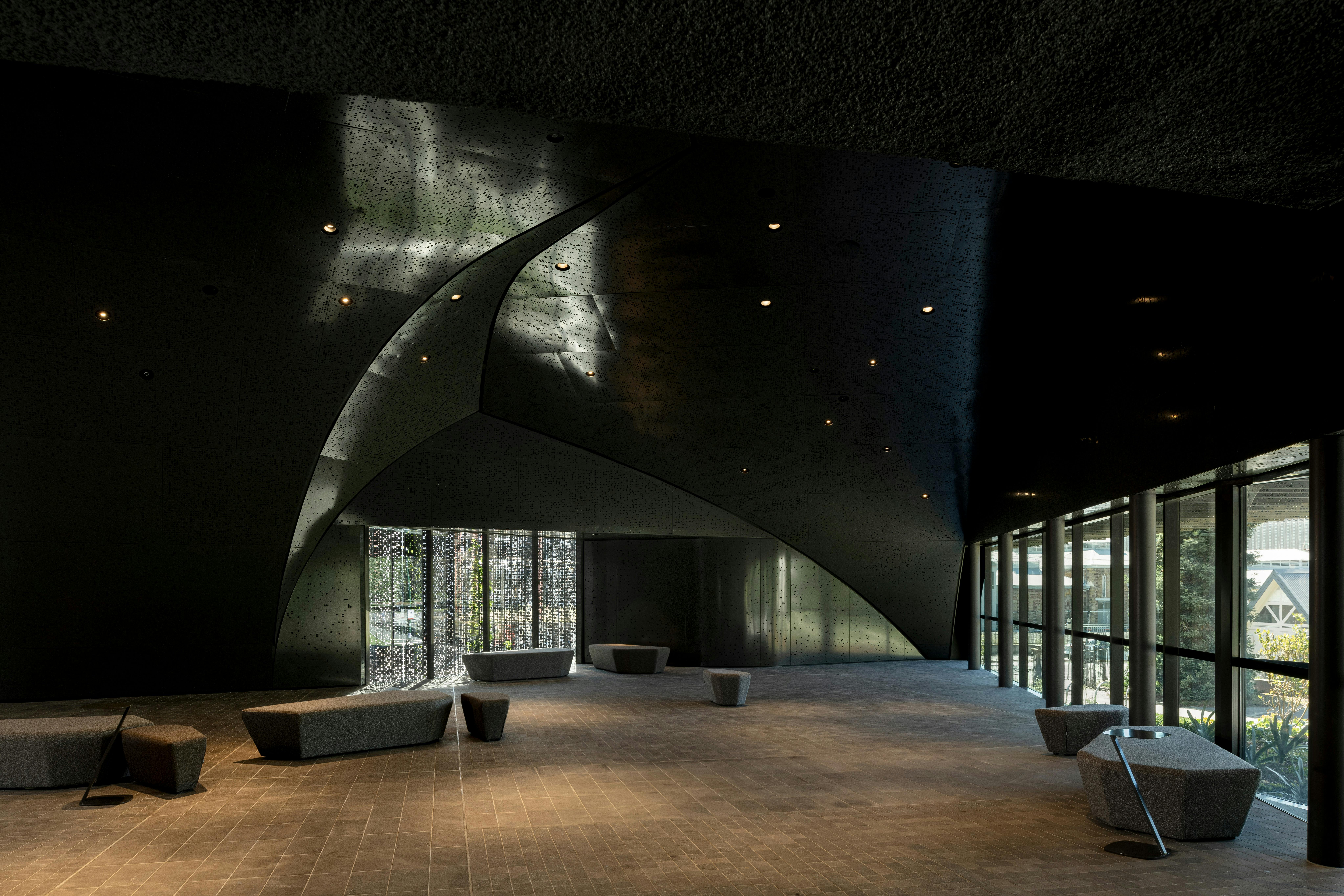 A dark grey, contempory space with curved walls and dappled light
