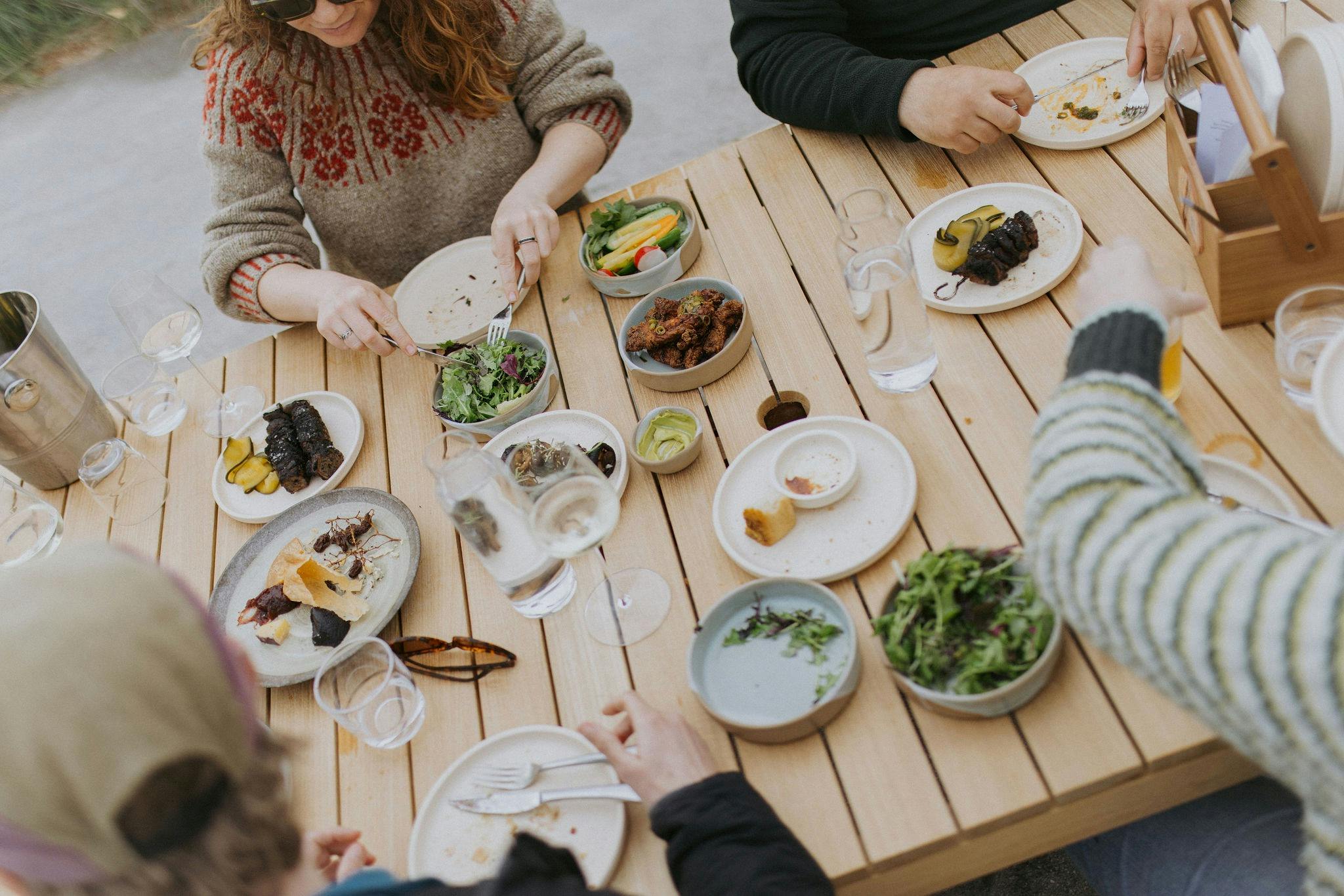 table with lots of plates of food and people sharing