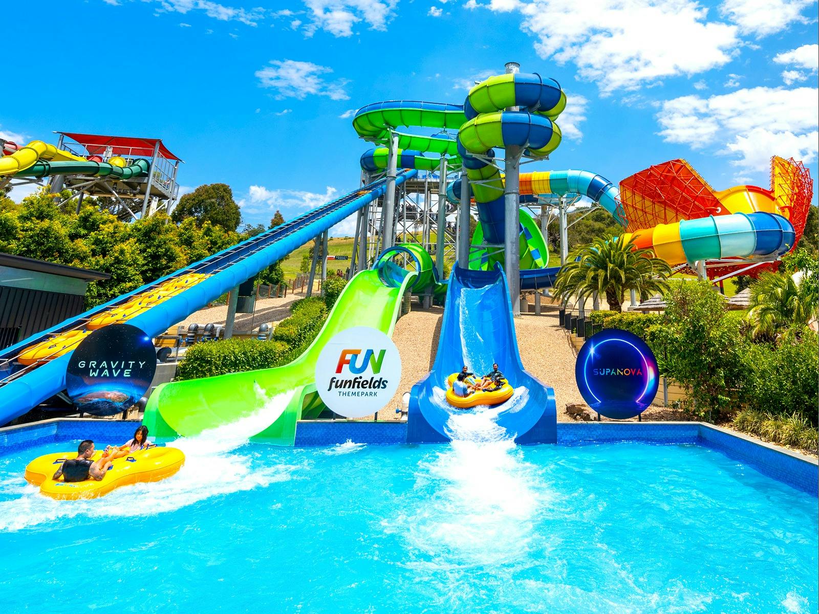 Long shot of two 9 storey high colourful waterslides called Gravity Wave and Supanova. Family fun
